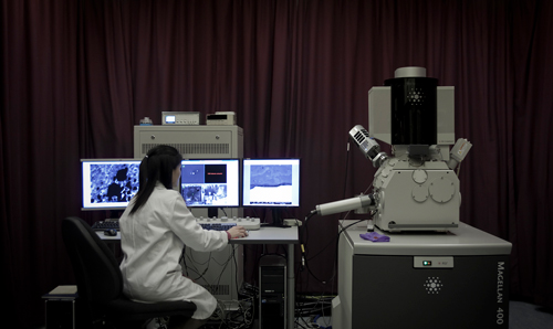 Researcher analysing images in lab on three PC screens
