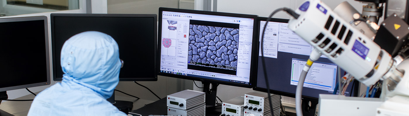 Researcher wearing cleanroom suit using lab computers