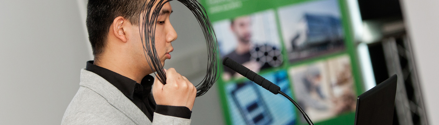 Researcher holding up graphene filament while speaking into a microphone